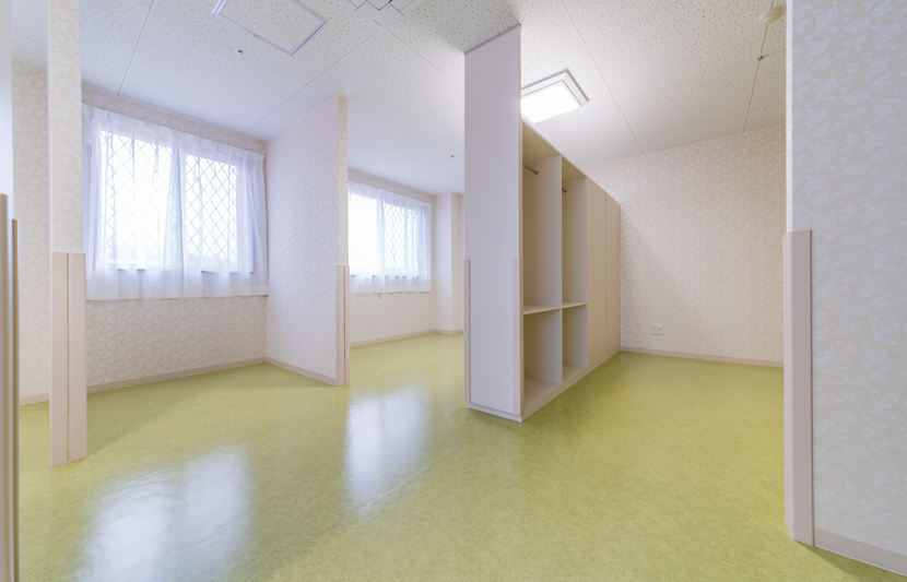 多床室。床を緑に暖かい内装をイメージ